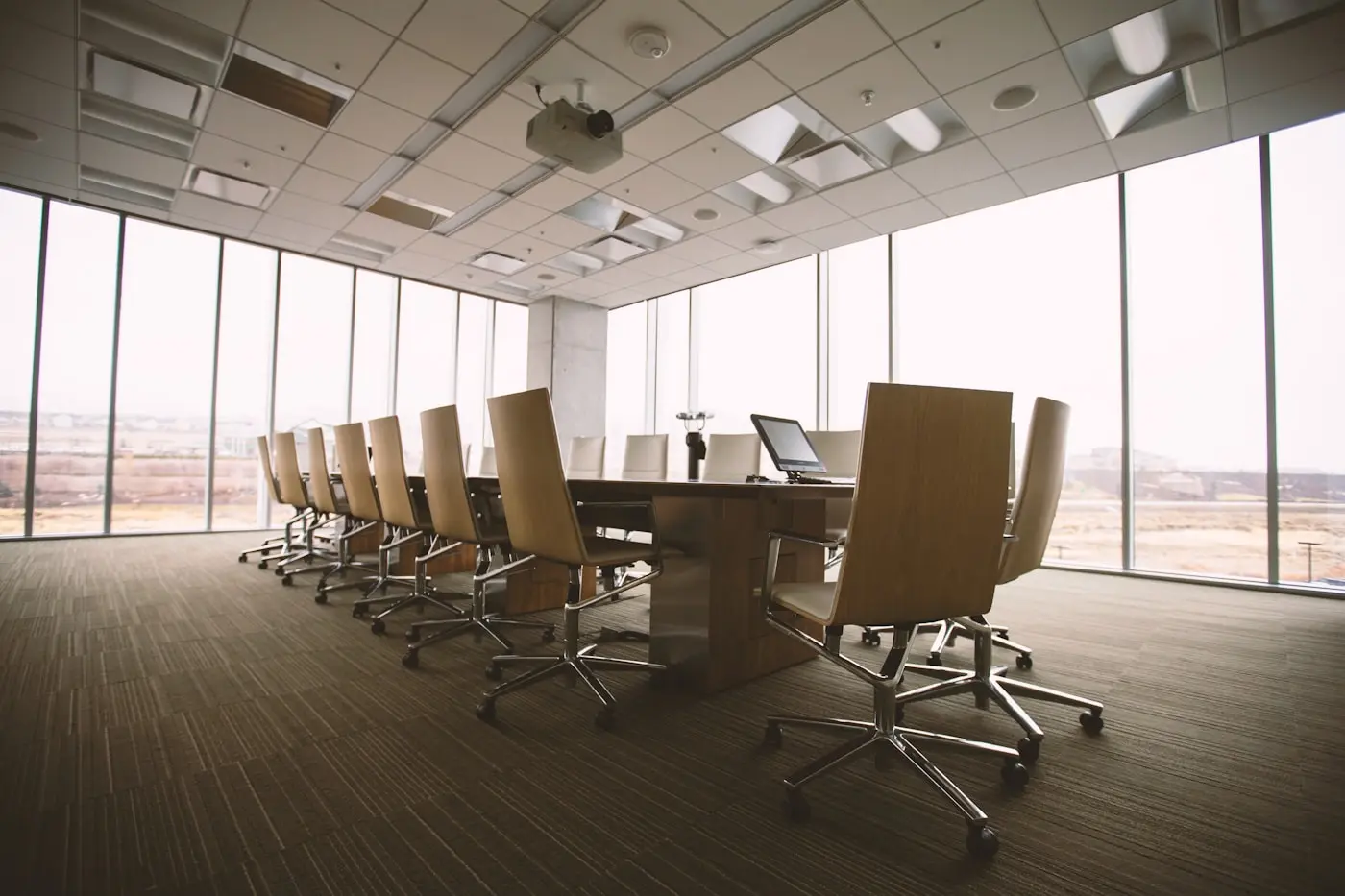 Empty boardroom with a long timber table, leather chairs and floor-to-ceiling windows