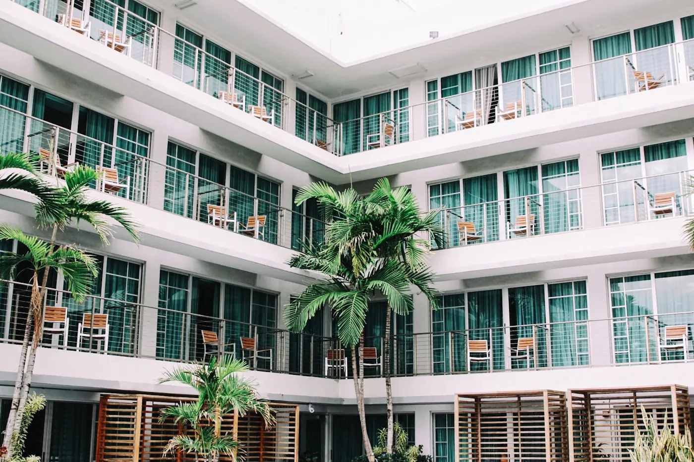 Hotel courtyard facade with repeating balconies, timber screens and palm trees